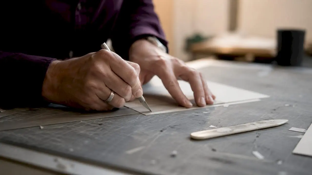 Close-up of hands cutting cardstock with craft knife