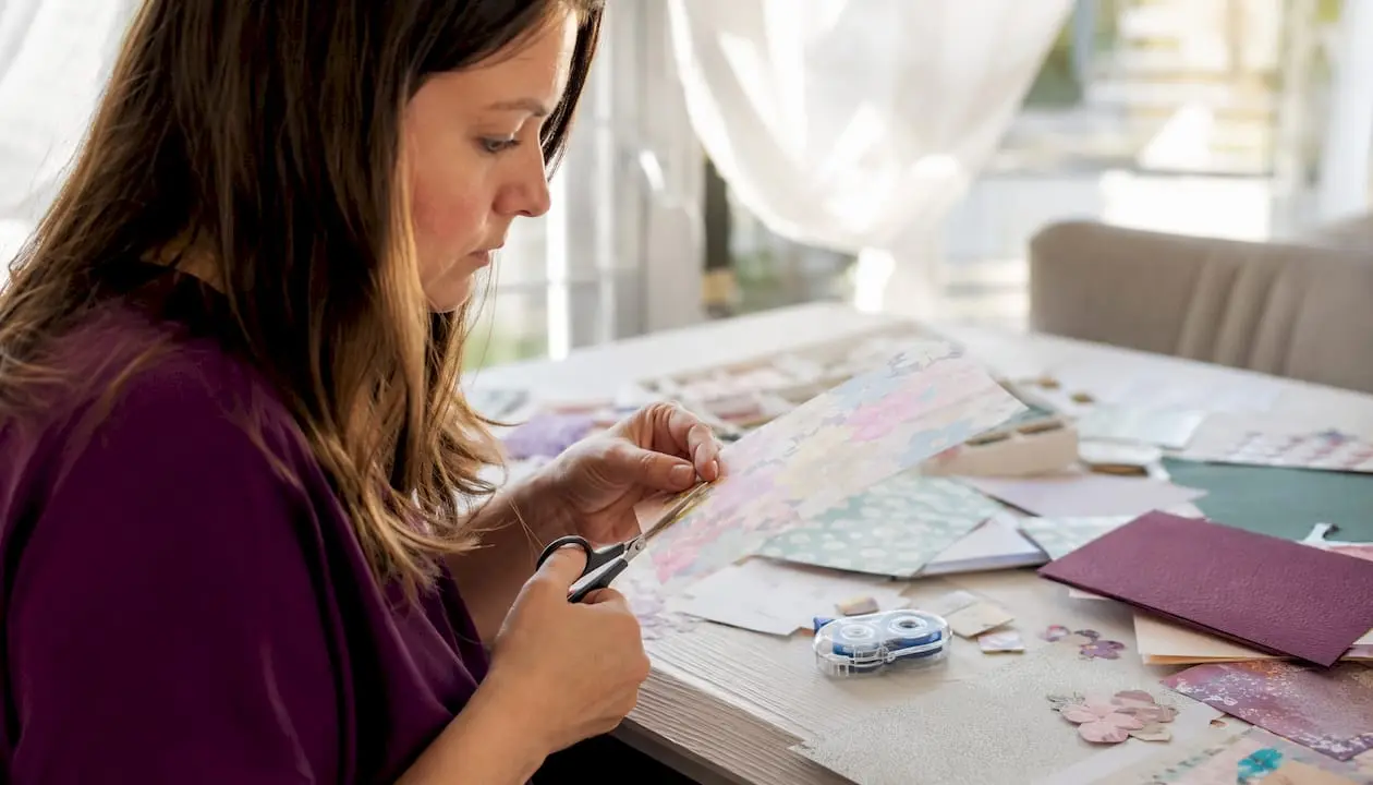 Female crafter cutting patterned paper at home studio