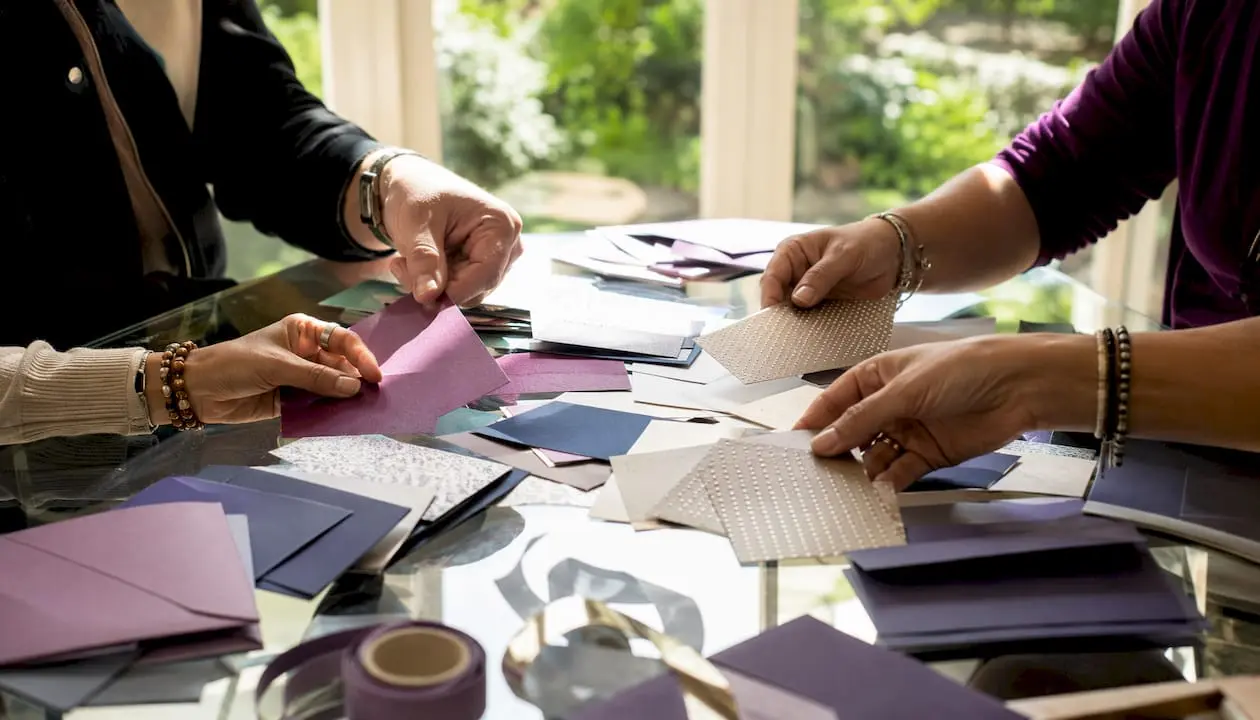 Hands sorting UK card stock samples on table