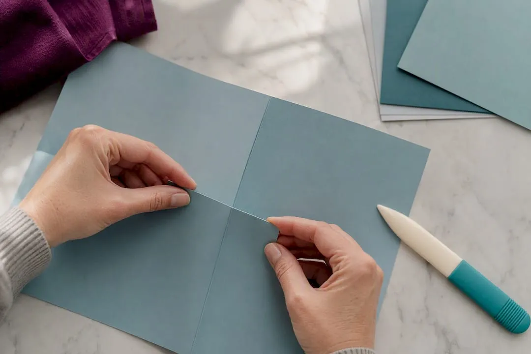 Hands aligning margins on folded cardstock panels