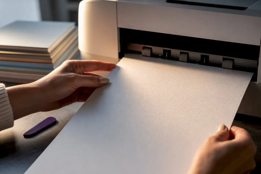 Hands guiding cardstock into rear printer feed
