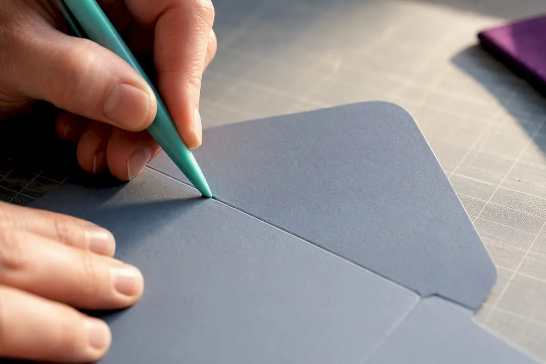 Hands scoring a cardstock envelope template